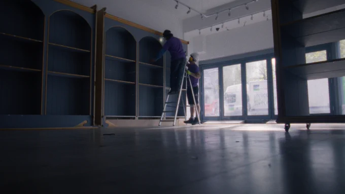 Artists' studio space being set up. Two people are working in the empty space. 