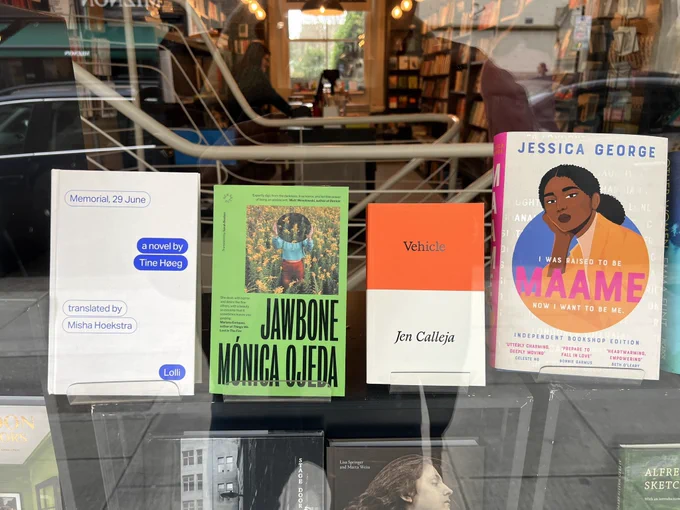 Four books in a shop window including and orange and white book
