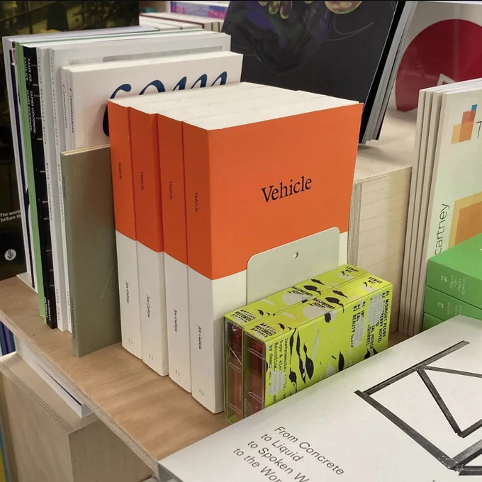 4 orange and white books standing together pressed between other books on a table