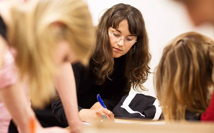 Group of 3 women sitting at a table working.