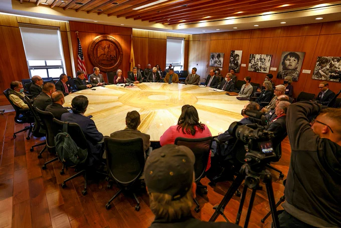 Governor, legislators seated around table 