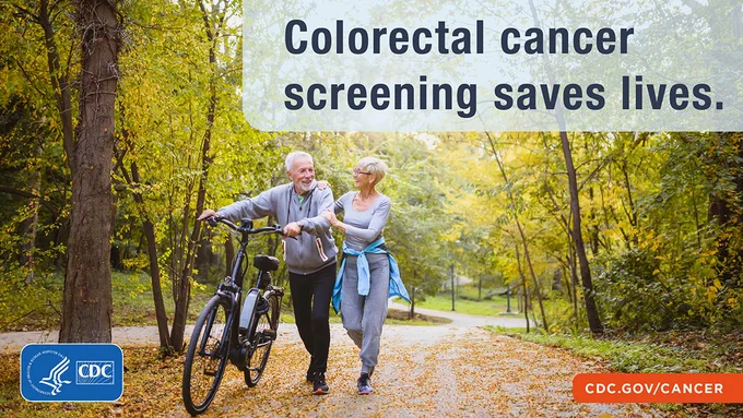 Older couple on a path in the woods on a fall day. He has a bicycle and she has placed her hands on his arm and shoulder. Text: Colorectal cancer saves lives