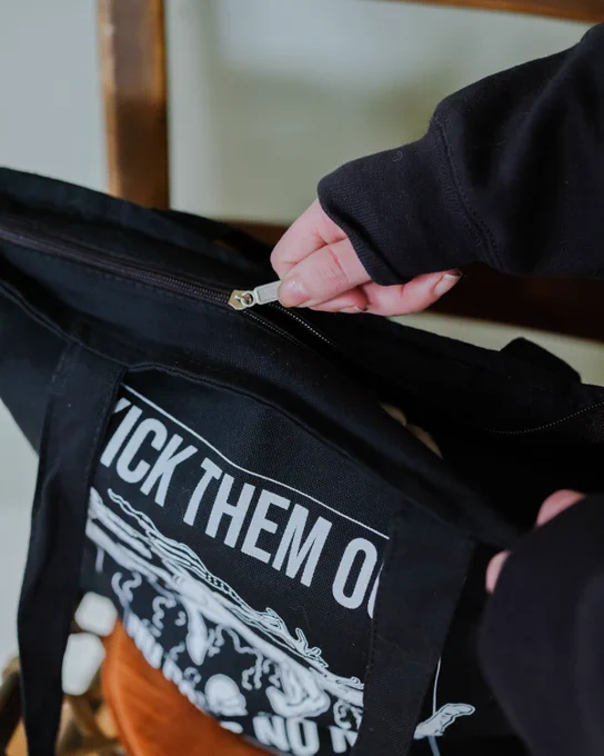 a close up photo of a black tote bag. it has two long handles and a zipper at the top.