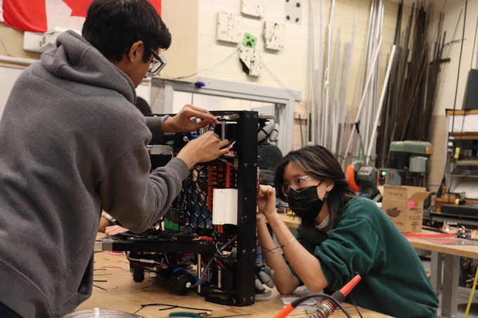 Two students fixing a robot.
