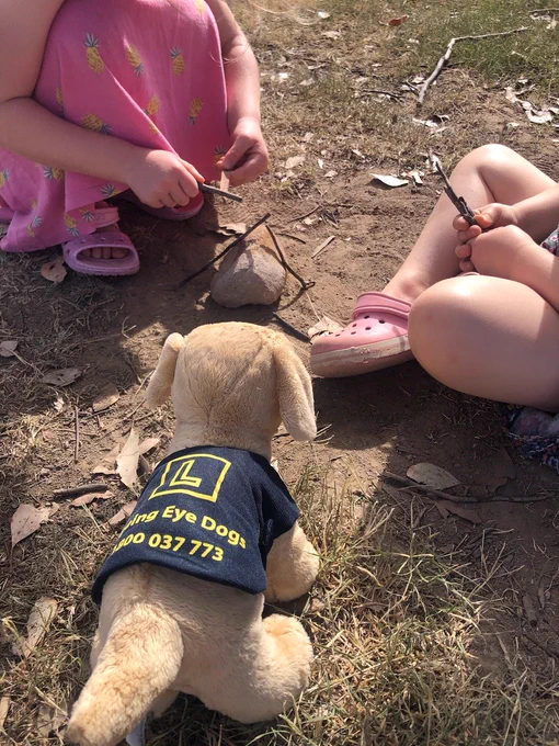 Sam sitting nearby two children making a campfire.