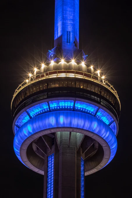 closeup of the CN Tower at night lit in blue / gros plan de la Tour CN de nuit éclairée en bleu