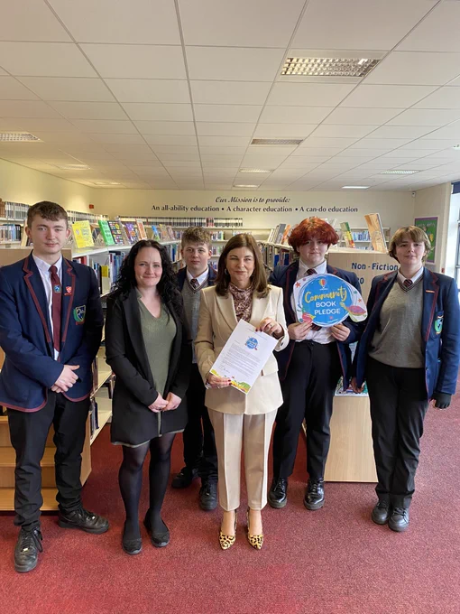 Sinéad standing in the school library with four pupils well as the school librarian from Oakgrove Integrated College.
