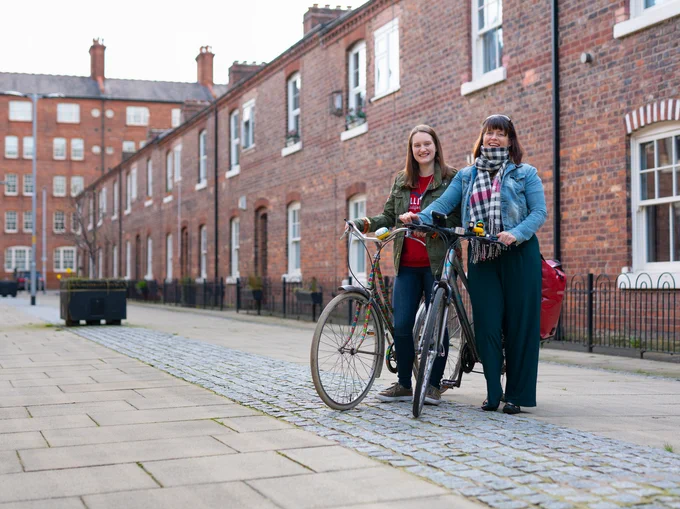 Two women stand with their bikes