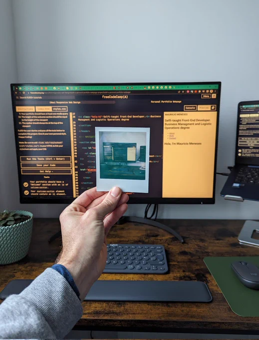 Polaroid photo whit a monitor behind it tha shows coding lines.