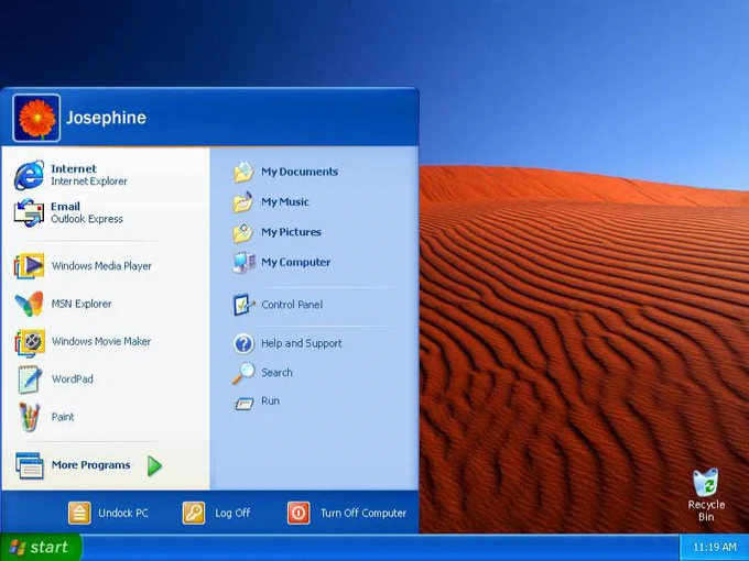 The image shows a computer using the Windows XP interface, the start menu is selected and the background is a red sand desert with a blue sky.