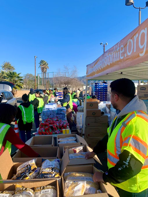 Volunteers, including Cal Poly Pomona marketing students, supporting the food distribution line for a drive through pantry at Sowing Seeds for Life. 