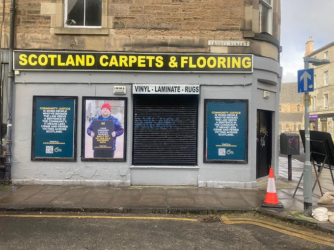 Three posters in a row on a shop front with signage that reads 'Scotland Carpets & Flooring'