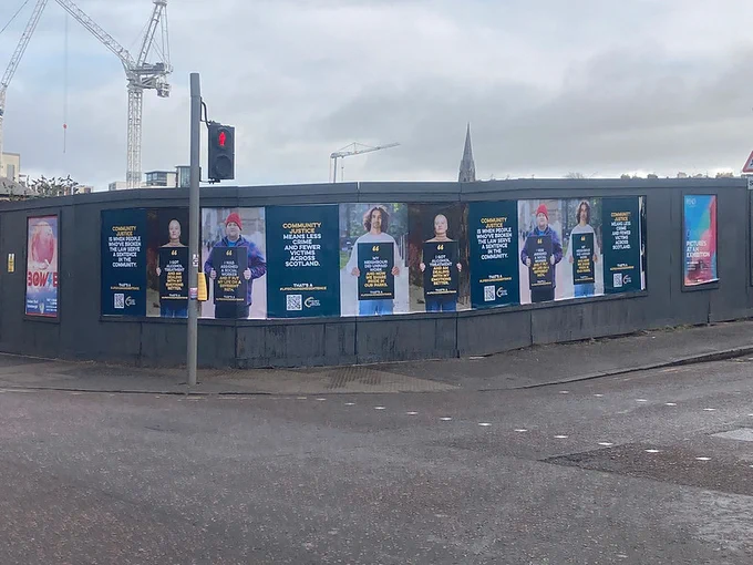 Ten posters in a row displayed on black hoarding
