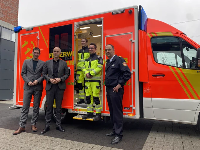 Oberbürgermeister Belit Onay, Feuerwehrdezernent Dr. Axel von Der Ohe, Feuerwehrchef Christoph Bahlmann und eine Rettungswagenbesatzung stehen vor dem ersten vollelektrischen Rettungswagen der Feuerwehr Hannover