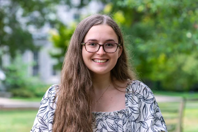 Anna Smith '22, wearing a white blouse with a leaf pattern, smiles for a headshot.