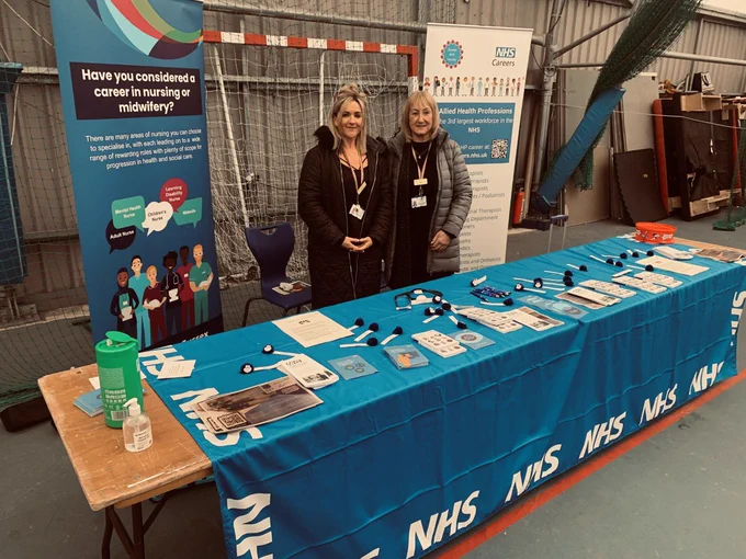 ESHT Integrated Education members of staff posing with the East Sussex Healthcare NHS Trust display at Eastbourne Schools Careers Fair, 10th March.