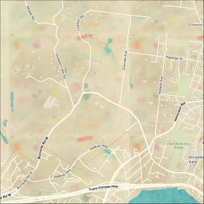 This is an up-close image of an aerial view of roads and highways near Saanich, British Columbia. The land mass of Canada has been turned a fluffy-textured beige and multicoloured “fun-fetti” vanilla cake texture. Buildings and roads are symbolized in a way that resembles white buttercream frosting. A waterbody is just slightly visible in the bottom right corner, and is symbolized with a spongey turquoise texture. 