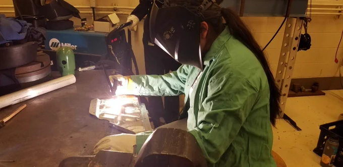 Picture of high school student practicing TIG welding on scrap metal.