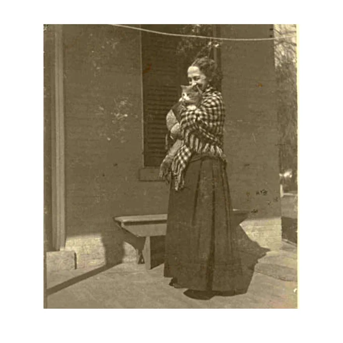 archival photo of Lavinia Dickinson holding a cat on the front porch