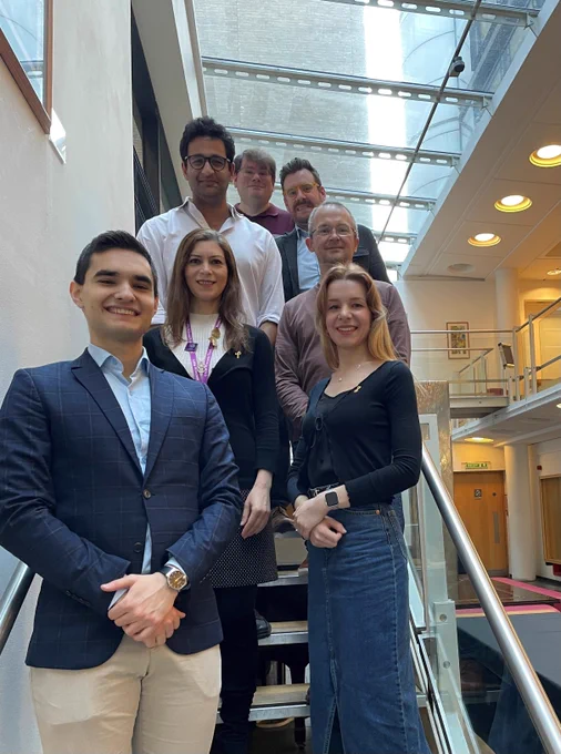 A group of 7 people on the stairs, smiling at the camera in smart, casual dress. They are the research team behind the winning image.