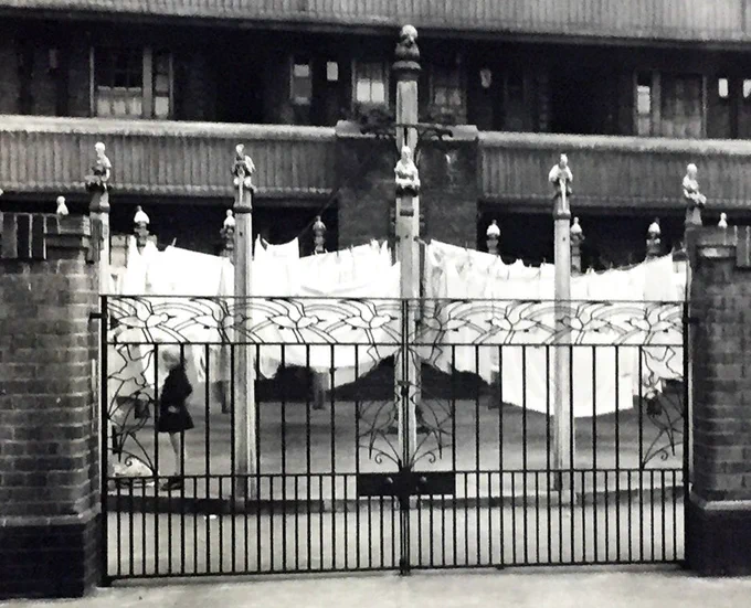 A set of drying posts in a circle in a courtyard with washing hanging from them and tailors on top. 