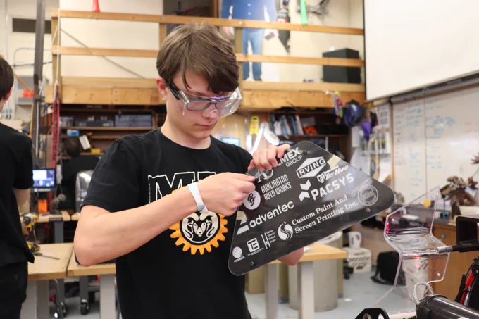  Student placing plate on robot.