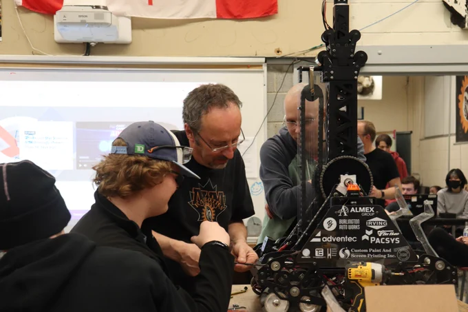 Mentors and students fixing robot.