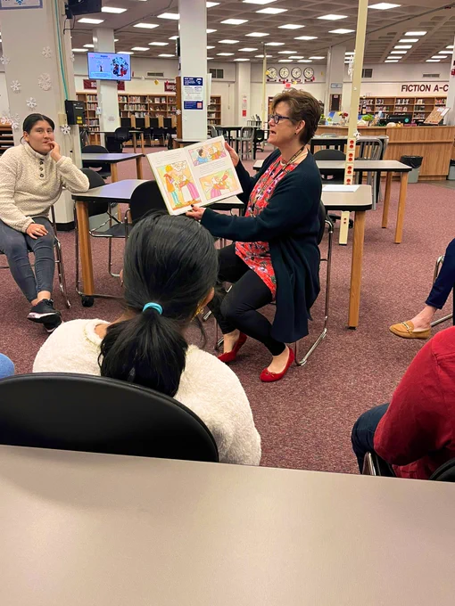 Mrs. B reading aloud to students sitting in a circle