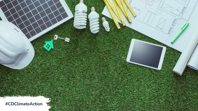 A hard hat, solar panels, lightbulbs, a tablet and a floorplan document splayed out on grass