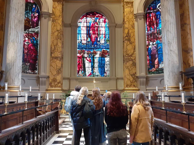 A group of students in front of Edward Burne Jones stained glass windows at St Philip's cathedral, Birmingham