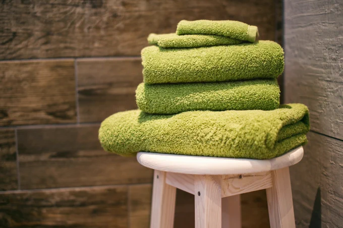stack of green towels on a stool, photo by Denny Müller, Unsplash