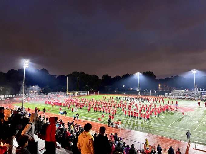 The Shaker Heights High School marching band performs on the football field under the lights.