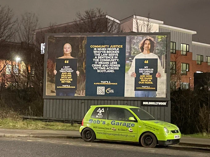 Two large posters with people holding billboards and one with text only in Portobello, Edinburgh