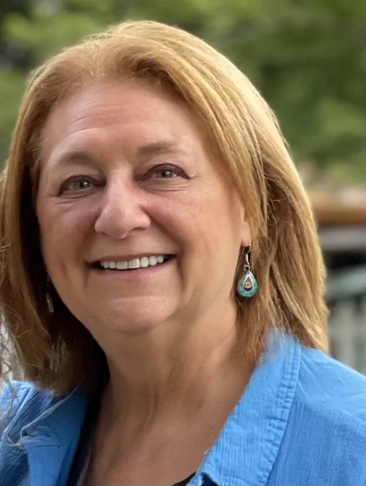 Nancy Potok is a white woman with light hair smiling at the camera. 