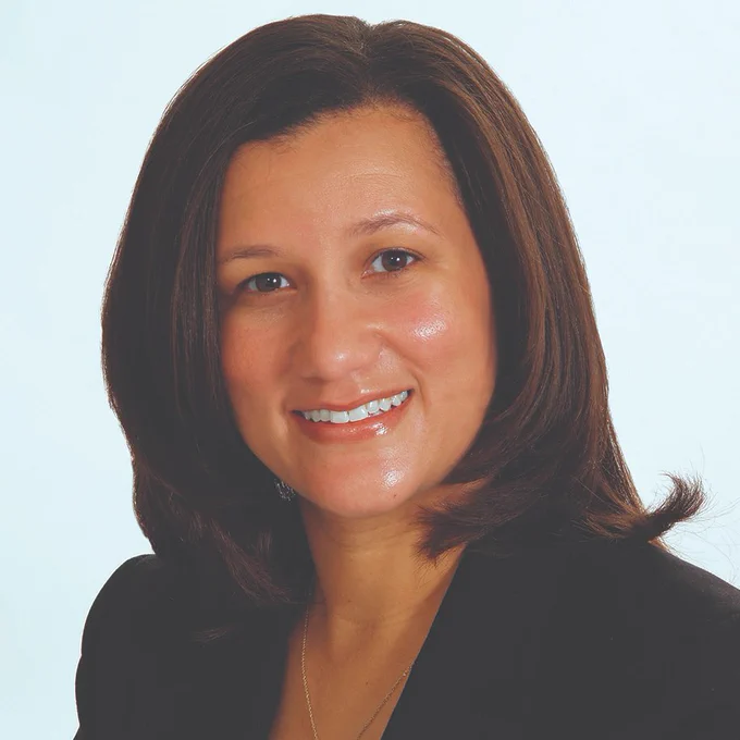 Dionne Price is a black woman smiling at the camera with dark, long straight hair. 
