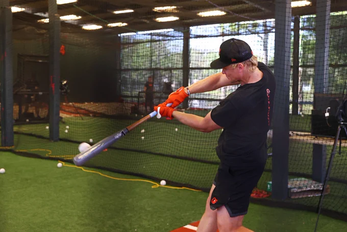 Kyle Stowers making contact with a ball as he swings his bat in the batting cage