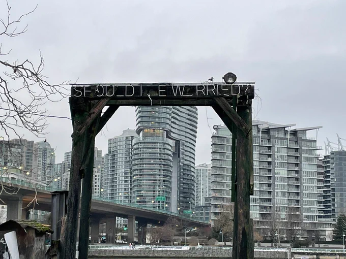 The same neon on, not lit up, against a grey overcast sky. The sign is now barely legible it’s so damaged.