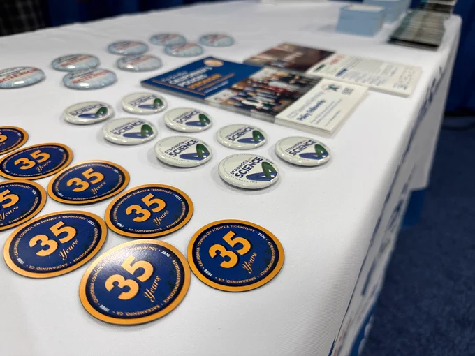 Magnets, buttons and various swag on a table in an exhibitor booth.