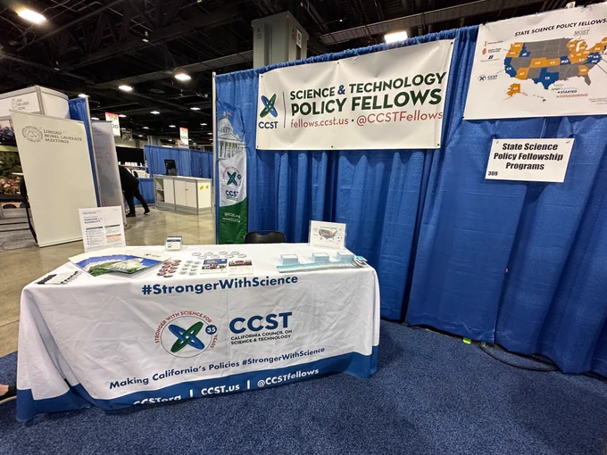 A table with materials on it in an exhibitor space in front of a curtain.