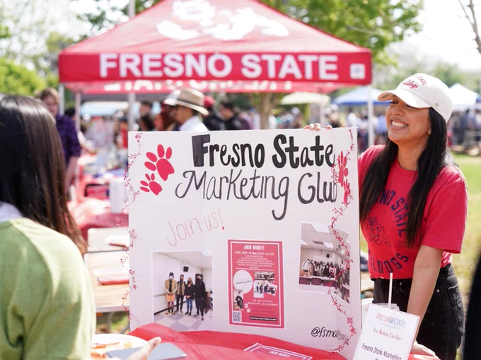 A student speaking while standing next to a poster board showcasing their club