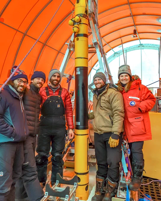 Four people stand in winter gear in a tent