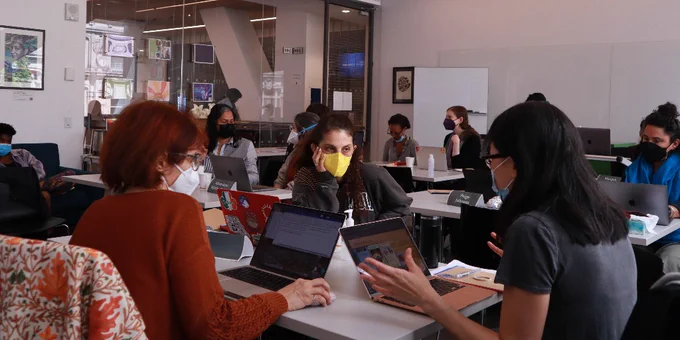 People sitting talking in groups in the Digital Humanities Center, with their laptops open on the tables in front of them