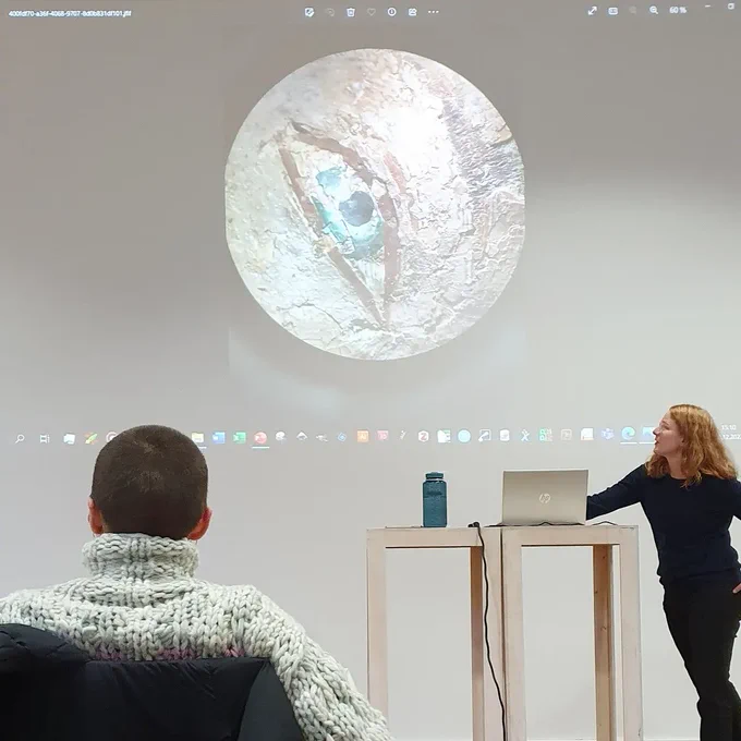 The photo of the eye is presented in a PowerPoint presentation. A woman stands next to a laptop for the presentation and another sits in front of it.