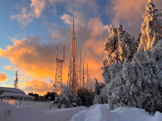 snow-covered trees and area near the radio transmitters in Mt. Wilson as the sun rises and peaking through a cloudy Friday morning