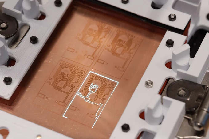 A fiber laser engraver is cutting circuit traces on a copper based substrate.