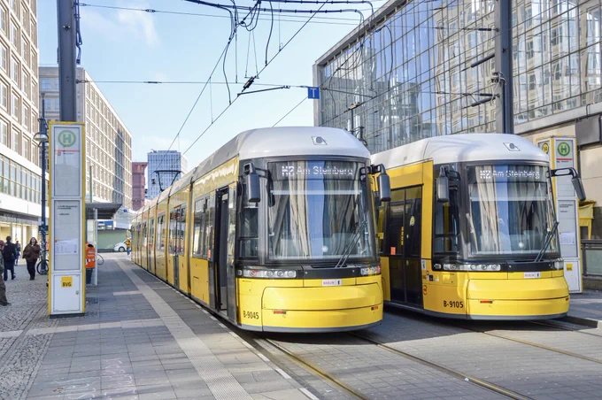 Two bright yellow trams wait at the platform side by side at the Alexanderplatz station in Berlin.
