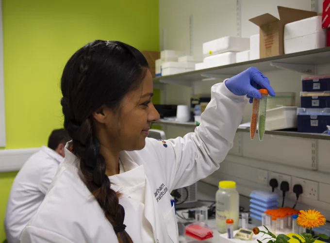 Side-on profile of Dr Melissa Salmon in the EI labs holding up a green and orange materials in test tubes