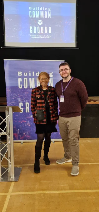 Former Hillingdon Cllr Beulah East and I in the foreground with backdrops of signs from the London Co-operative Party displaying the confidence theme, Building Common Ground