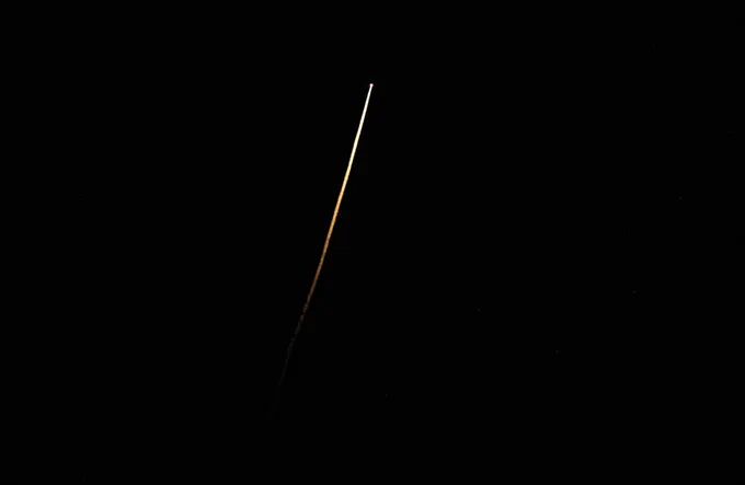 Crew-5's Dragon Endurance spacecraft is seen here as a bright white streak against a totally dark sky; light trails behind it, slowly fading to orange and then black. NASA/Keegan Barber