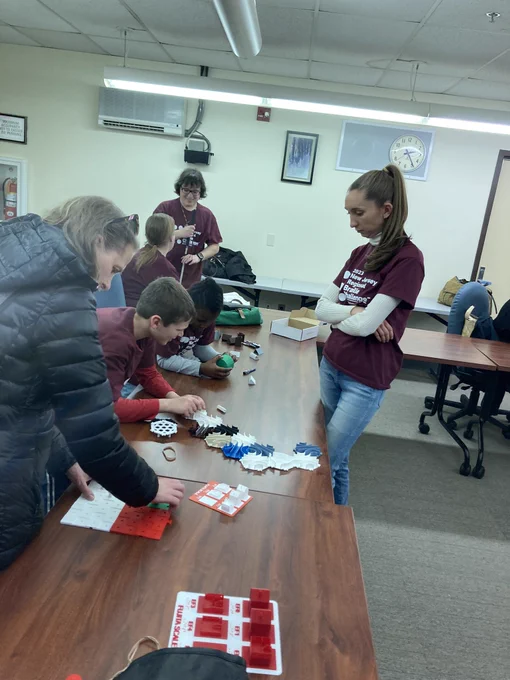 Student participants and parents playing with STEM boards, marble run, and fraction measuring cup